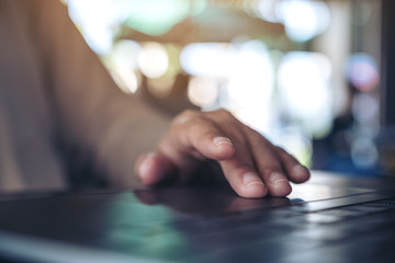 Closeup image of hands using and touching on laptop touchpad on wooden table