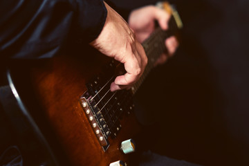 Fototapeta premium Close-up fingers of the musician touch the strings of a six-string electric guitar.