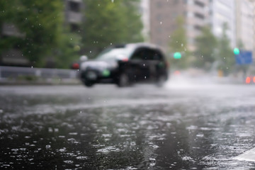 Heavy rain falls on asphalt with blurry cars (focus on road surface)
