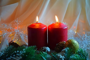 Christmas candles and green twigs on the background of lights.