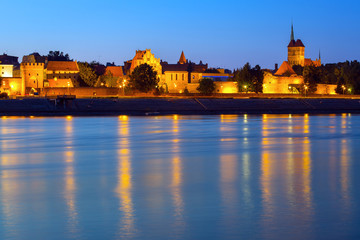 Old town of Torun at night reflected in Vistula river, Poland