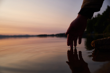 Human hand touching the fresh water from lake. Close-up. Lifestyles concept.