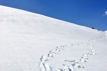 Fototapeta na wymiar footsprint on the hill covered with snow under blue sky