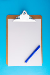Clipboard and pencil on blue background with selective focus and crop fragment