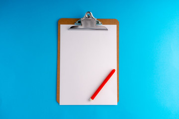 Clipboard and pencil on blue background with selective focus and crop fragment
