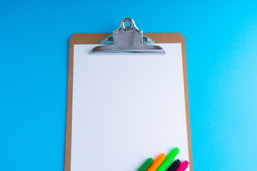 Clipboard and pencil on blue background with selective focus and crop fragment