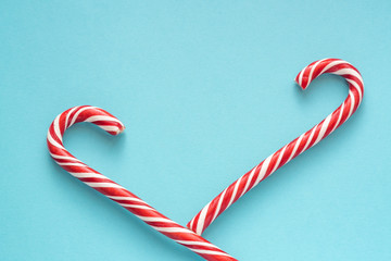 Merry Christmas and Happy New Year greeting card. Two candy canes on blue background with copy space for your text.