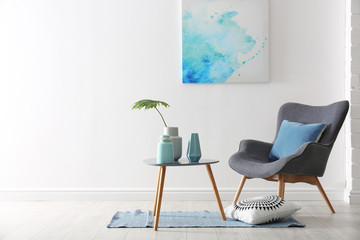 Living room interior with vases on table and armchair near white wall. Space for text