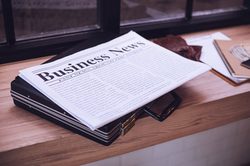 Newspaper, briefcase on a wooden table in the cafe