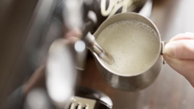 Female Barista Steaming a Mug of Hot Milk for a Latte. Espresso Coffee Preparation in Super Slow Motion