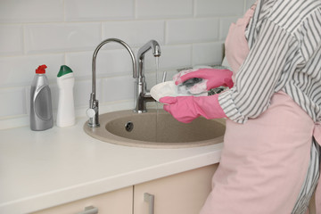 Woman doing washing up in kitchen sink, closeup view. Cleaning chores
