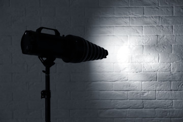 Professional photo studio lighting equipment near brick wall. Space for text