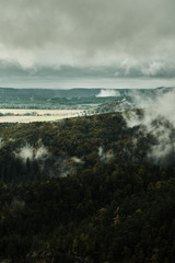 Deadpan dark misty rainy morning landscape with the sand rocky montains in Czech Saxon Switzerland in autumn colors