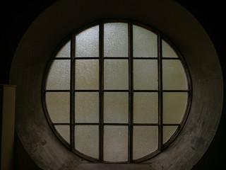 Old round window with interesting architecture in a dark room, low light and creepy atmosphere