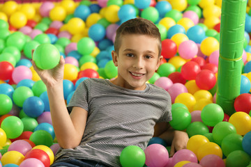 Fototapeta na wymiar Cute little child playing in ball pit at indoor amusement park