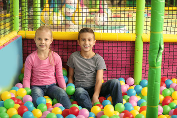 Fototapeta na wymiar Cute little children playing in ball pit at indoor amusement park