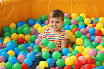 Fototapeta na wymiar Cute little child playing in ball pit at indoor amusement park