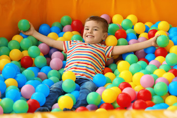 Cute little child playing in ball pit at indoor amusement park