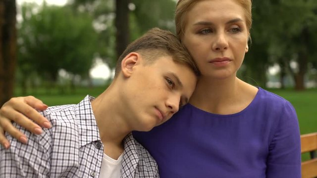 Young son in despair putting head on mothers shoulder feeling calmness and love