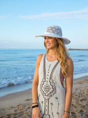 blonde young girl on the beach with dress and hat