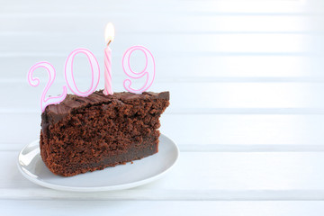 festive dish of the year a piece of chocolate cake decorated with a number of a burning candle