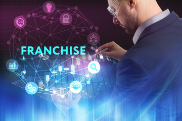 The concept of business, technology, the Internet and the network. A young entrepreneur working on a virtual screen of the future and sees the inscription: Franchise