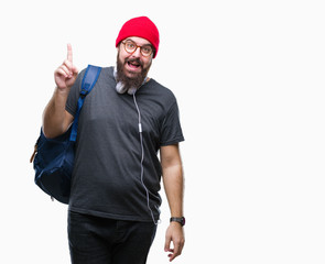 Fototapeta premium Young hipster man wearing red wool cap and backpack over isolated background pointing finger up with successful idea. Exited and happy. Number one.