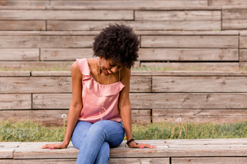 portrait of a Happy young beautiful afro american woman sitting on wood floor and smiling. Spring or summer season. Casual clothing