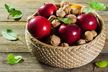 red ripe apples and nuts in a basket on a tree background 2