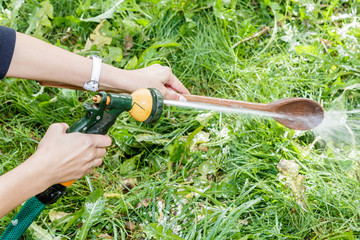 man's hands wash dishes with water hose