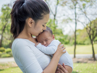 Happy family, Pretty woman holding a newborn baby in her arms on nature park in summer