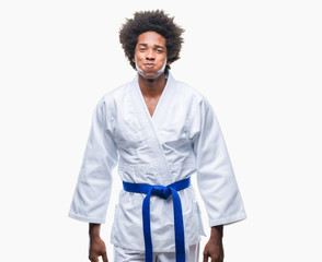Afro american man wearing karate kimono over isolated background puffing cheeks with funny face. Mouth inflated with air, crazy expression.