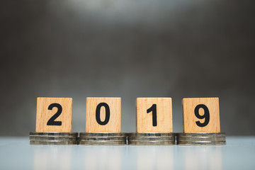 Obraz premium Wooden block year 2019 with stack coins using as business and financial concept
