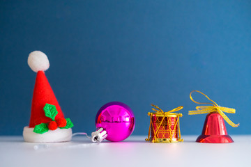 Christmas Concept with copy space.Small Santa Claus hat with ornament balls,bell,pineconse and small present.