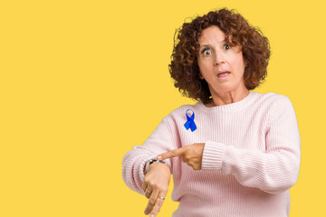 Middle ager senior woman wearing changeable blue color ribbon awareness over isolated background In...