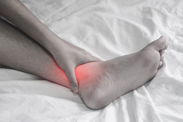 Men touch over ankle pain on bed.