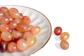 Grape lies on a white plate with a wooden background. isolate