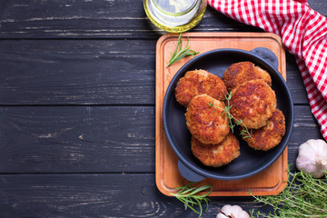 Homemade cutlets with herb and spices  on  black wooden background.