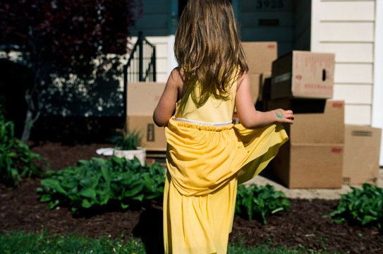 little girl in front of home with moving boxes