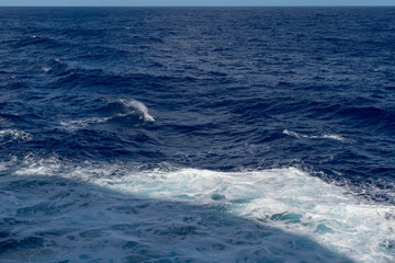 Naklejka na ściany i meble Dark blue sea and white sea foam on the tops of the waves.