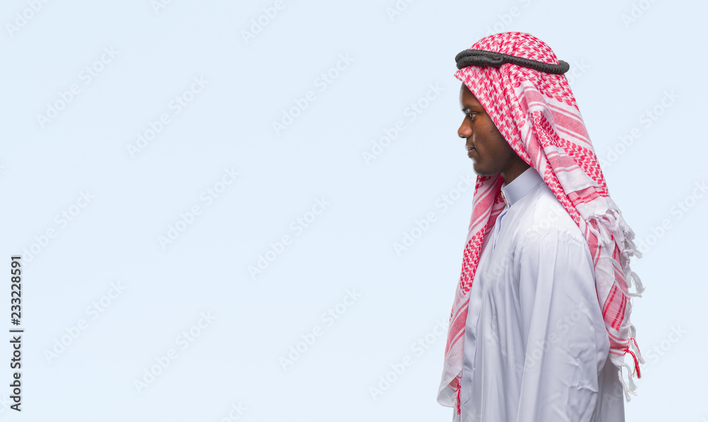 Wall mural young arabic african man wearing traditional keffiyeh over isolated background looking to side, rela