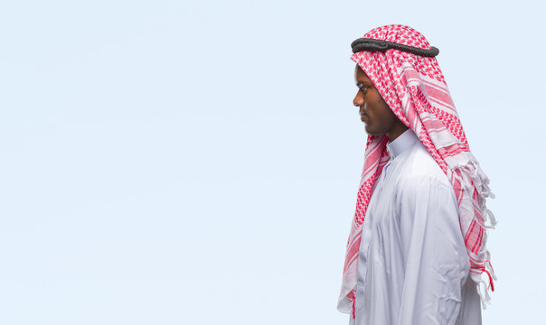 Young arabic african man wearing traditional keffiyeh over isolated background looking to side, relax profile pose with natural face with confident smile.