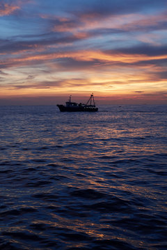 Fishing ship at sea, in sunset time