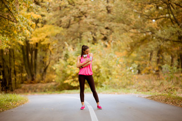 Fototapeta premium Young woman have a break during training in the autumn forest