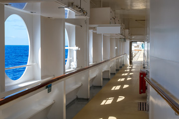 Promenade deck of a cruise ship on a Sunny day with views of the sea horizon.