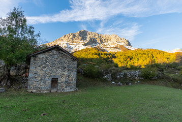 Fototapeta na wymiar Old house in the middle of a valley at the foot of the mountain in the national park of Picos de Europa in the zone of Sajambre, Leon (Spain) used by the shepherds