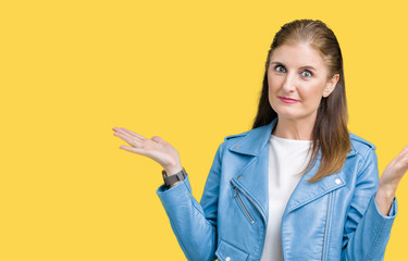 Beautiful middle age mature woman wearing fashion leather jacket over isolated background clueless...