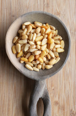 Pine nuts on wood spoon with bamboo cutting board. background.