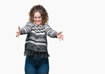 Beautiful brunette curly hair young girl wearing glasses over isolated background looking at the camera smiling with open arms for hug. Cheerful expression embracing happiness.