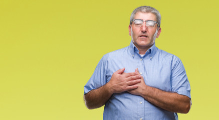 Handsome senior man wearing glasses over isolated background smiling with hands on chest with closed eyes and grateful gesture on face. Health concept.